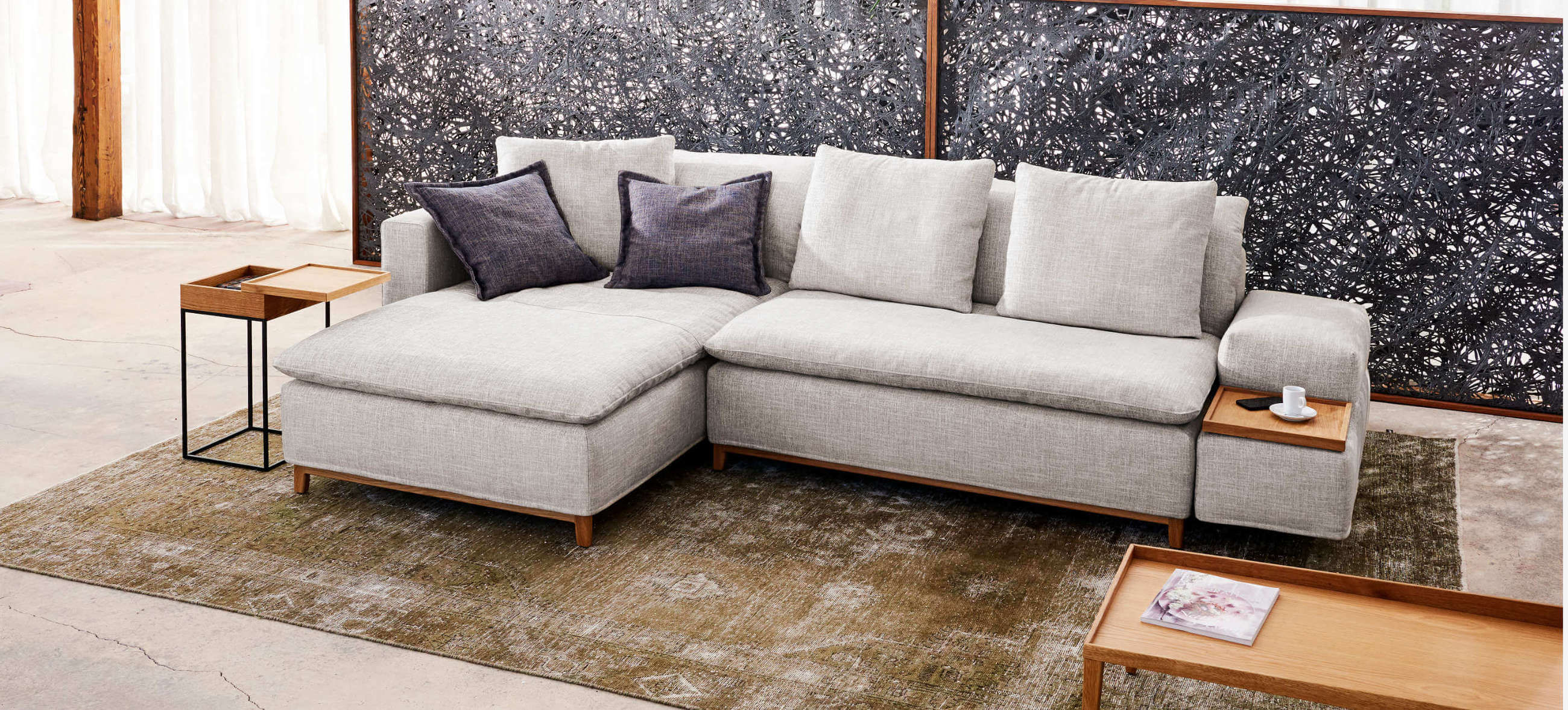 Kompaktes Ecksofa Isla von Signet – Stilvoll und funktional. Kompaktes Ecksofa Isla von Signet in hellem Stoff mit Holzdetails und gemütlichen Kissen.