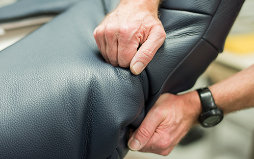Handwerkliches Geschick und Präzision bei der Lederverarbeitung. Das Leder wird auf einen Jori Sessel gezogen.